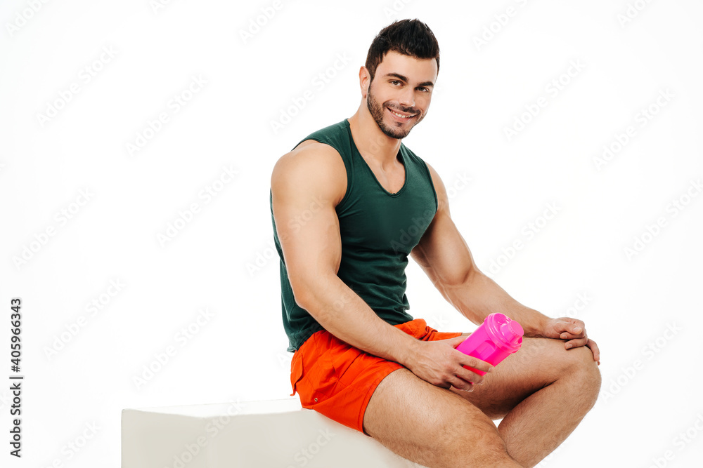 Muscular man sitting on a white steps and smiling on white background Muscular man sitting on a white steps and smiling on white background