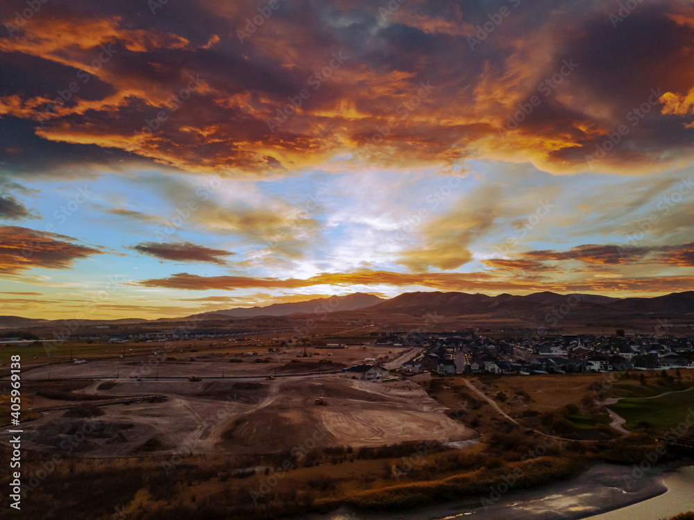 Naklejka premium Dramatic clouds at sunset over suburban neighborhood - aerial