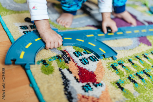 High angle shot of a kid playing train track toys on the carpet at home photo