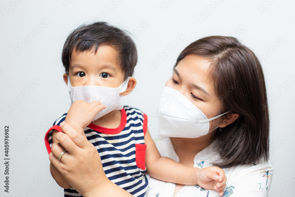 Mother hold baby boy wear medical face mask protect from infection of virus
