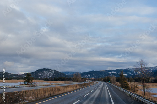 Scenic asphalt road among snow-capped mountains in winter. Old Mission State Park, hwy 90, Idaho, USA, 2-8-2020