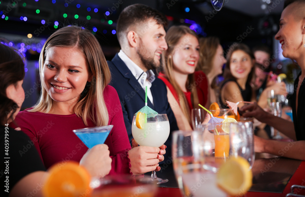 Young attractive woman with cocktails having fun with friends at nightclub