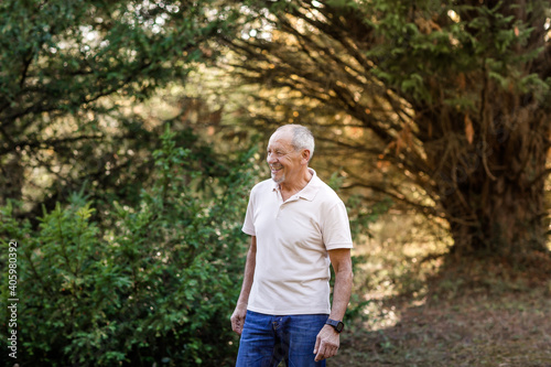 Portrait of happy and smiling senior man taking a walk in the countryside