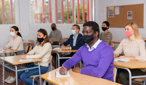 African-american student wearing protective mask among students in university classroom © JackF