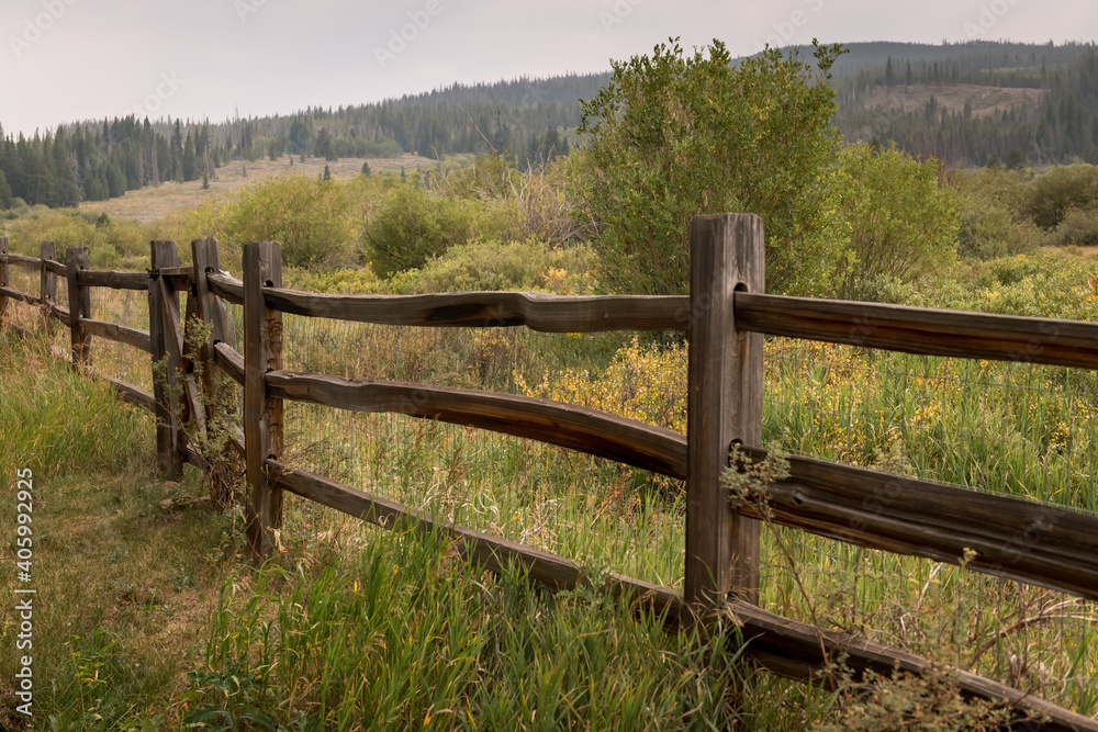 Old fence in Colorado overlooking a pasture of grass and trees