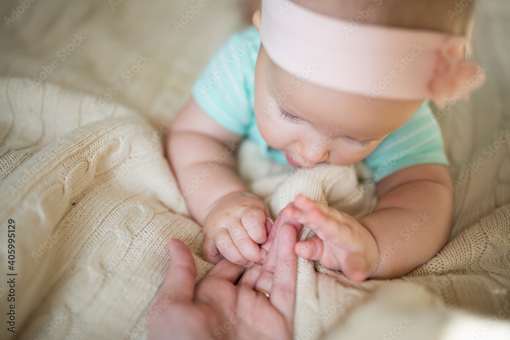 Caucasian blonde baby six months old lying on cozy knitted blanket at home. Kid wearing cute green clothing Caucasian blonde baby six months old lying on cozy knitted blanket at home. Kid wearing cute green clothing