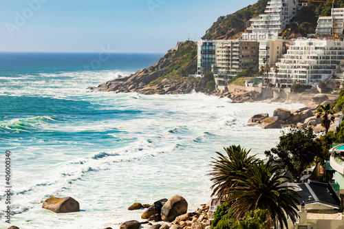 Urban waterfront town buildings on a forested hill in Cape Town, South Africa, and a wavy seascape