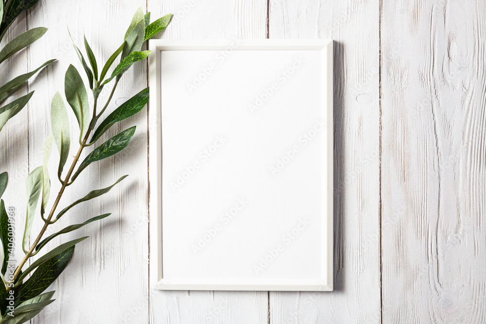White photo frame with a sprig of eucalyptus on a white wooden table. Minimalistic, gentle mock up White photo frame with a sprig of eucalyptus on a white wooden table. Minimalistic, gentle mock up