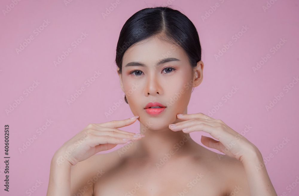 Youthful smiling Asian woman with hand touching face isolated on pink background for beauty and skin care concepts Youthful smiling Asian woman with hand touching face isolated on pink background for beauty and skin care concepts