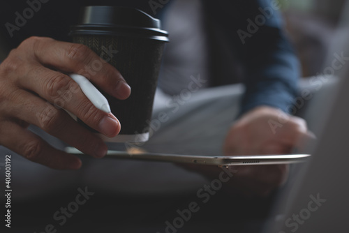 Close up of man hand holding digital tablet and cup of coffee during working from home