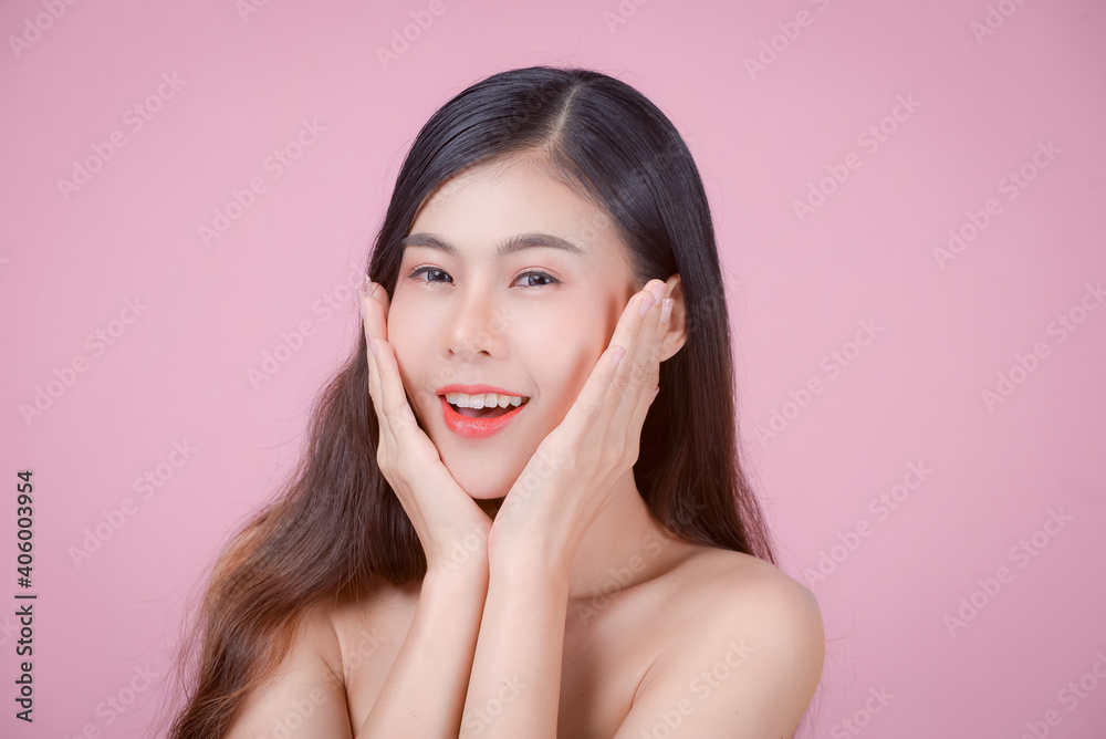 Youthful smiling Asian woman with hand touching face isolated on pink background for beauty and skin care concepts Youthful smiling Asian woman with hand touching face isolated on pink background for beauty and skin care concepts