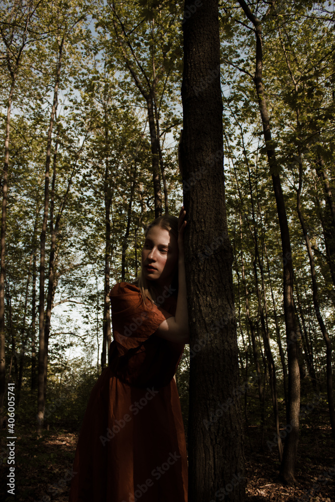 Portrait of a beautiful mysterious woman with blond hair in the forest. like a fairytale. Warm tone	
