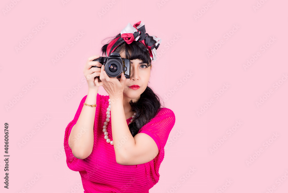 Like taking pictures. Closeup woman Holding camera pretty smiling pinup girl button shirt thinking about love career money looking hopeful to side, retro vintage 50's hairstyle isolated on color pink 