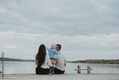 Young happy family sitting on the pier in the summer