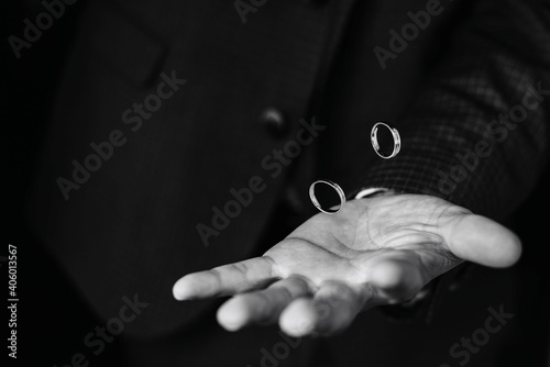 pair of gold wedding engagement rings fly over the groom's hand