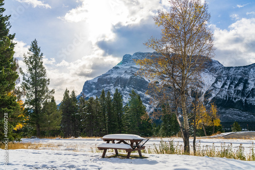 Tunnel Mountain Campground wooden bench in snowy autumn sunny day. Mount Rundle in the background. Banff National Park, Canadian Rockies. © Shawn.ccf