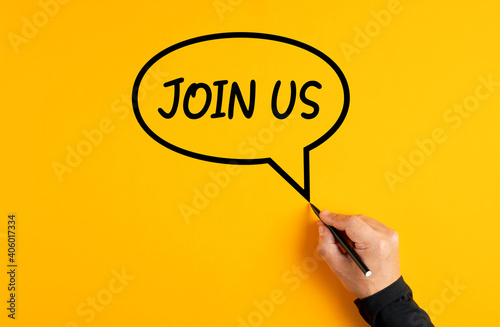 Male hand drawing a speech balloon with the word join us on yellow background. Job employment or membership subscription photo