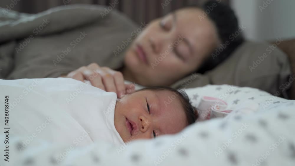 sleeping asian woman mother holding baby on bed but infant still awake. infant not sleeping problem at night. concept of exhausted mother syndrome. sleeping asian woman mother holding baby on bed but infant still awake. infant not sleeping problem at night. concept of exhausted mother syndrome.