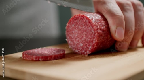 Human hands Cutting Salami Sausage On Wooden Board