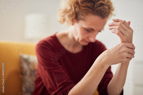 Woman with hand pain sitting on a couch at home. photo
