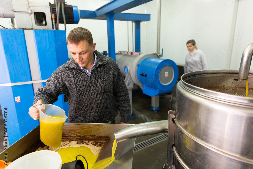 Man engaged in traditional olive oil production, controlling process of oil decanting Stock