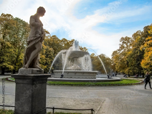 Rococo sculpture and fountain in the Saxon Garden in Warsaw on an autumn day. Beautiful old public park with yellow trees in the capital of Poland