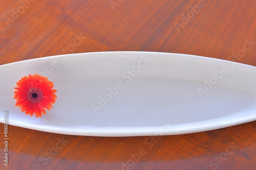 Gerbera.  float a flower on the water.  Top view photo of White plate on walnut table .  This expensive antique furniture is made in England.  texture background with copy space. 