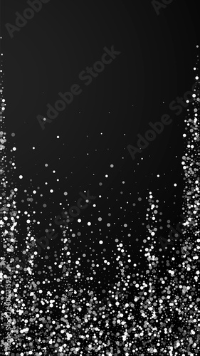 Random white dots Christmas background. Subtle flying snow flakes and stars on black background. Alluring winter silver snowflake overlay template. Ideal vertical illustration.