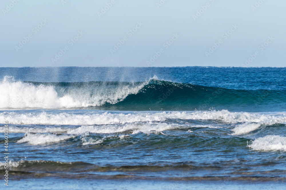 Wave breaking on a bright sunny morning. Perfect wave with offshore wind on a sand beach break