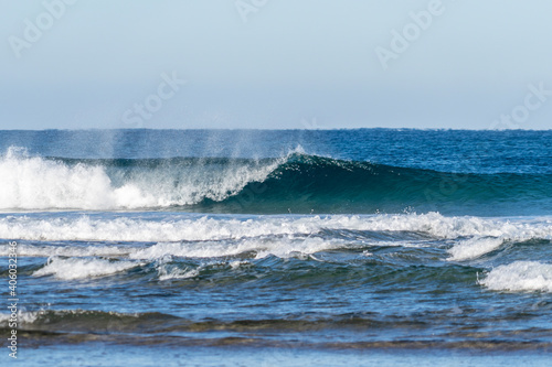 Wave breaking on a bright sunny morning. Perfect wave with offshore wind on a sand beach break