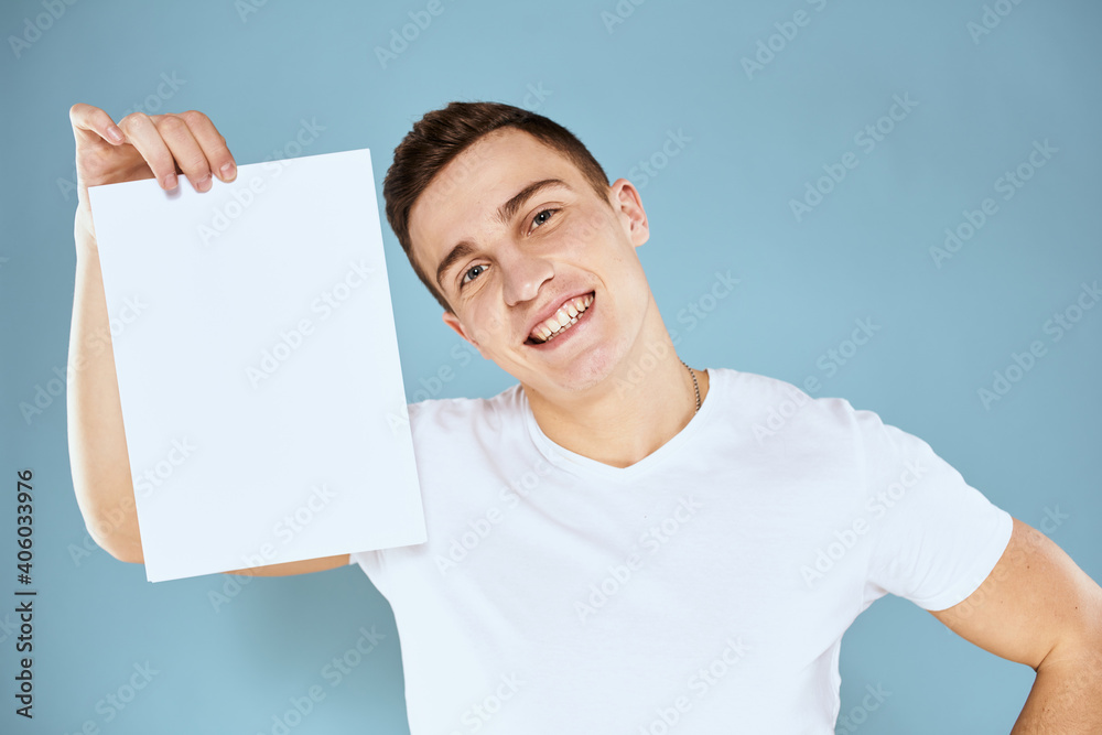 man holding a sheet of paper in his hands white t-shirt cropped view blue background man holding a sheet of paper in his hands white t-shirt cropped view blue background