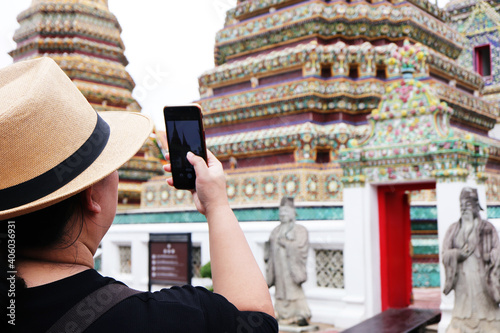 Asian woman tourists are taking photos with smartphone at Wat Phra Chettuphon Wimon Mangkhalaram Ratchaworamahawihan. photo