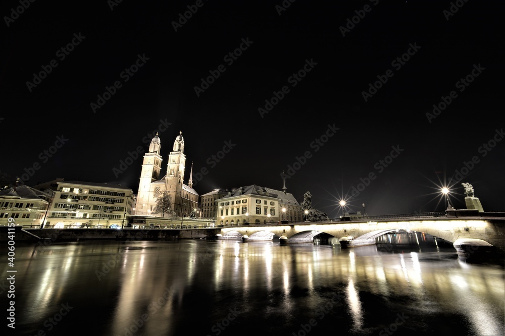 At night in snow on the Limmat with a view of Grossmünster, Münsterbrücke and Limmatquai in Zurich