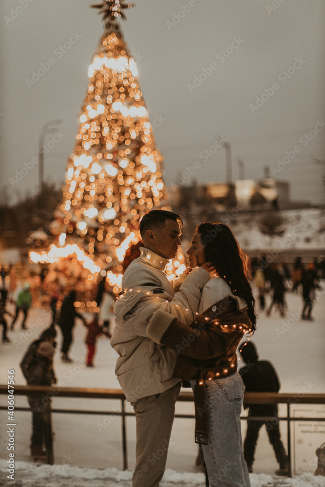 Obraz premium Young romantic couple in love outdoors in winter before Christmas. Two lovers are hugging and kissing in Saint Valentine's Day.