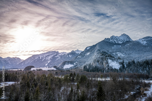 snowy wooded hahnenkamm mountain range in tyrol reutte with colorful and exciting clouds in winter