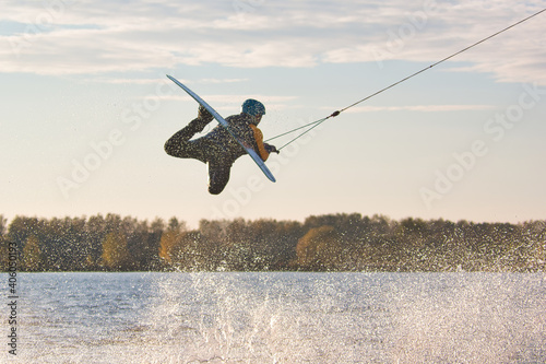 Wakeboarder making tricks. Low angle shot of man wakeboarding on a lake. Man water skiing at sunset. photo