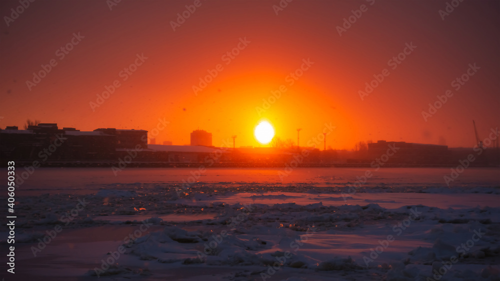 Beautiful sunrise in the city, near the frozen river. Winter morning landscape.