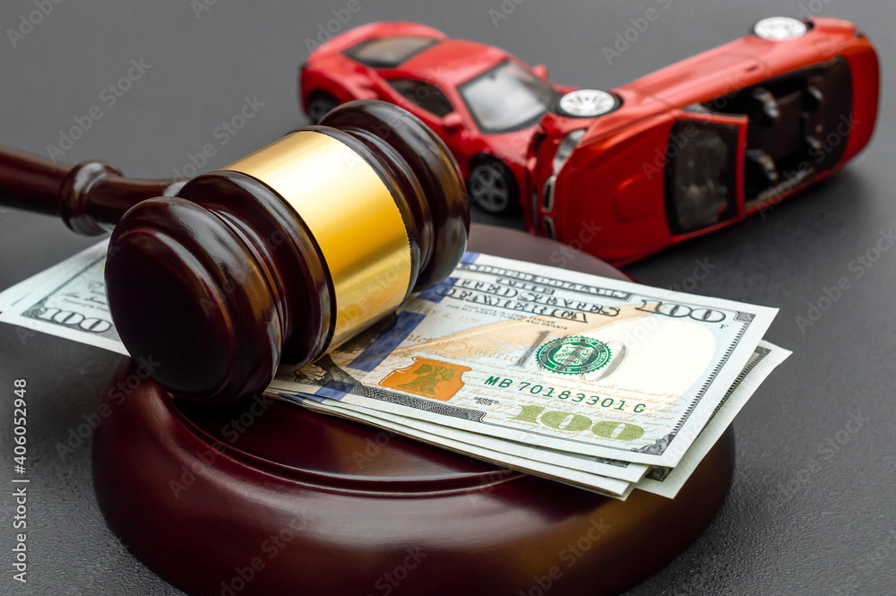Ternopil, Ukraine - December 27, 2020: Judge's gavel with money and  toy cars on black.