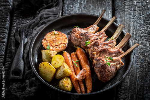 Roasted ribs of lamb with vegetables on black table
