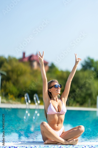 Young woman with hands up in pink bathing suit in pool