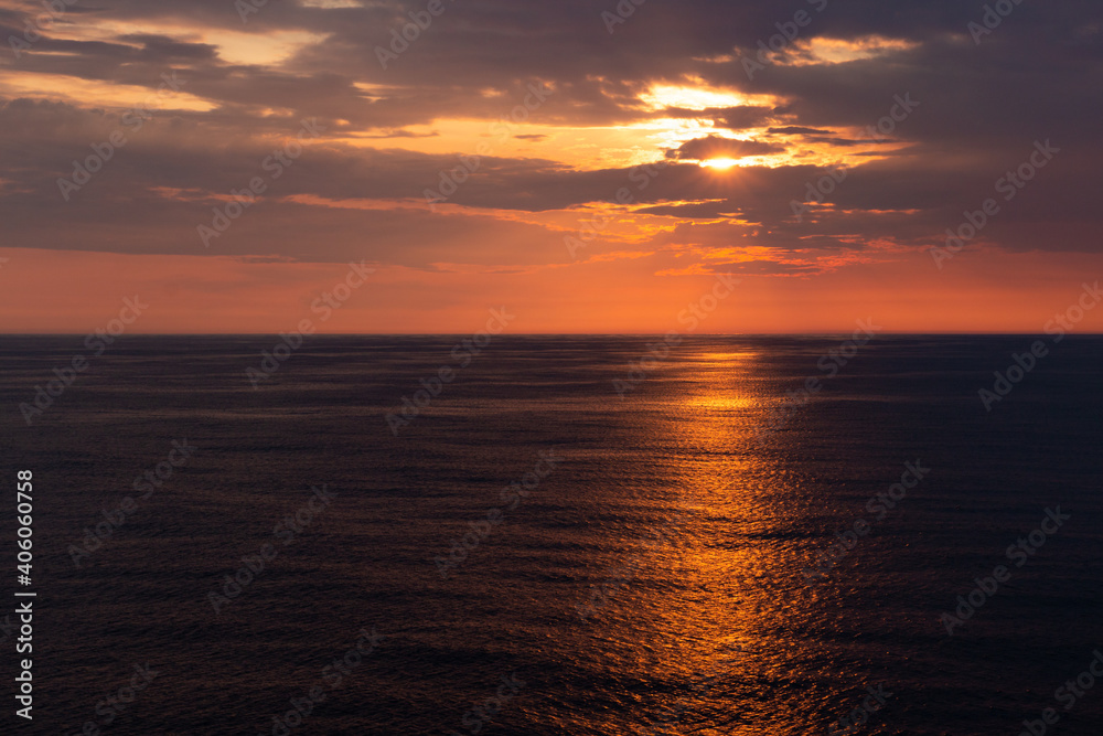 beautiful orange sunset over the dark sea wit an orange line of reflection.