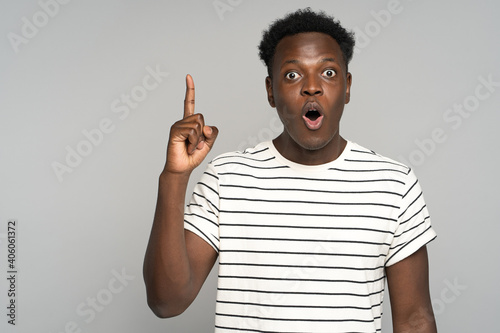 Konstfotografi Stupefied afro young man makes big eyes opens mouth widely, raise finger up, sur