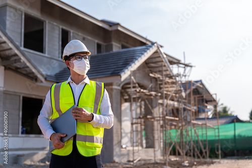 Portrait of Architect wearing a mask hold a laptop on a building construction site, Homebuilding Ideas and Prevention of Coronavirus Disease..