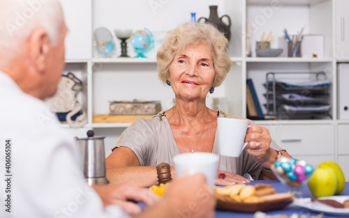 Happy senior woman drinking tea and chatting with his old friend at home