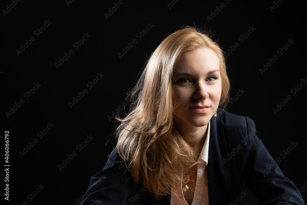 sitting on an orange chair. Smiling looking at camera, enjoying concept, on black background in studio, in blazer business woman, blonde