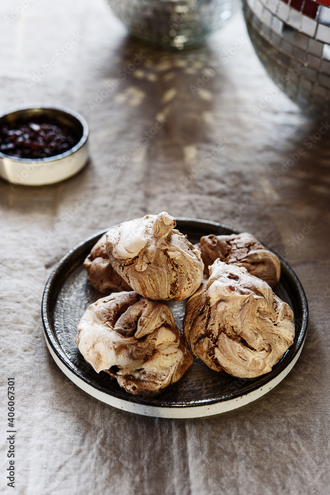 Homemade sweet chocolate meringue cookies on plate over greige linen tablecloth. Delicious and light holiday dessert Homemade sweet chocolate meringue cookies on plate over greige linen tablecloth. Delicious and light holiday dessert