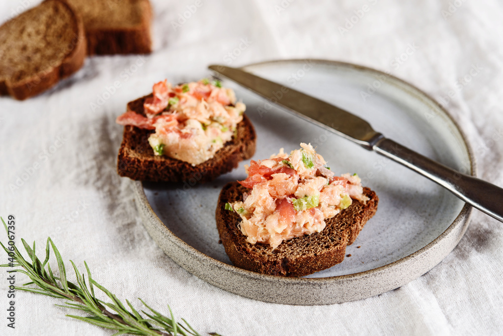Homemade French dish rilette or pate. Two toasts salmon rillettes (pate) on rye bread on plate over beige linen tablecloth. Selective focus Homemade French dish rilette or pate. Two toasts salmon rillettes (pate) on rye bread on plate over beige linen tablecloth. Selective focus
