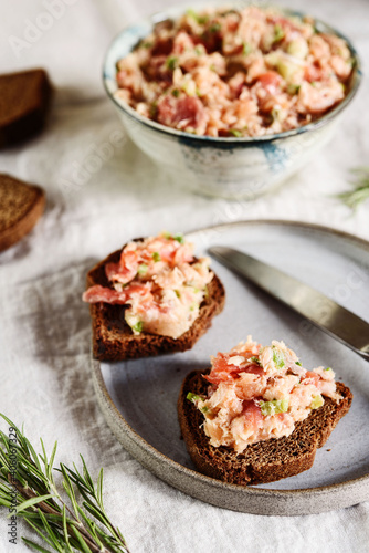 Homemade French dish rilette or pate. Two toasts salmon rillettes (pate) on rye bread on plate over beige linen tablecloth. Selective focus