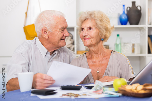 Positive mature couple with papers and laptop at home.