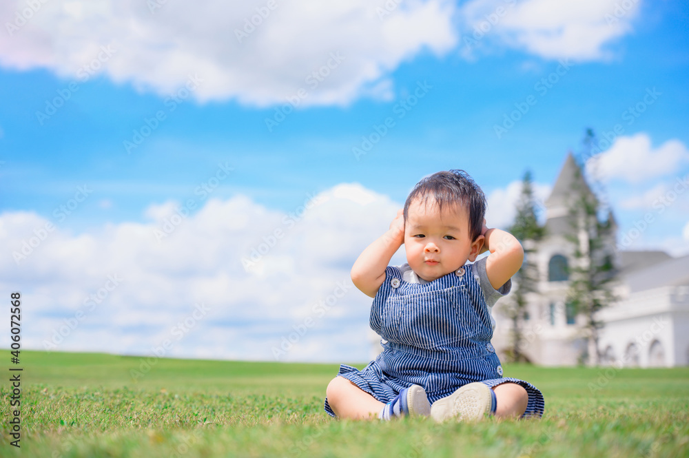 Boy among green grass s on a summer day. A small child has fun in the fresh air. Baby explores the nature with blue sky Boy among green grass s on a summer day. A small child has fun in the fresh air. Baby explores the nature with blue sky